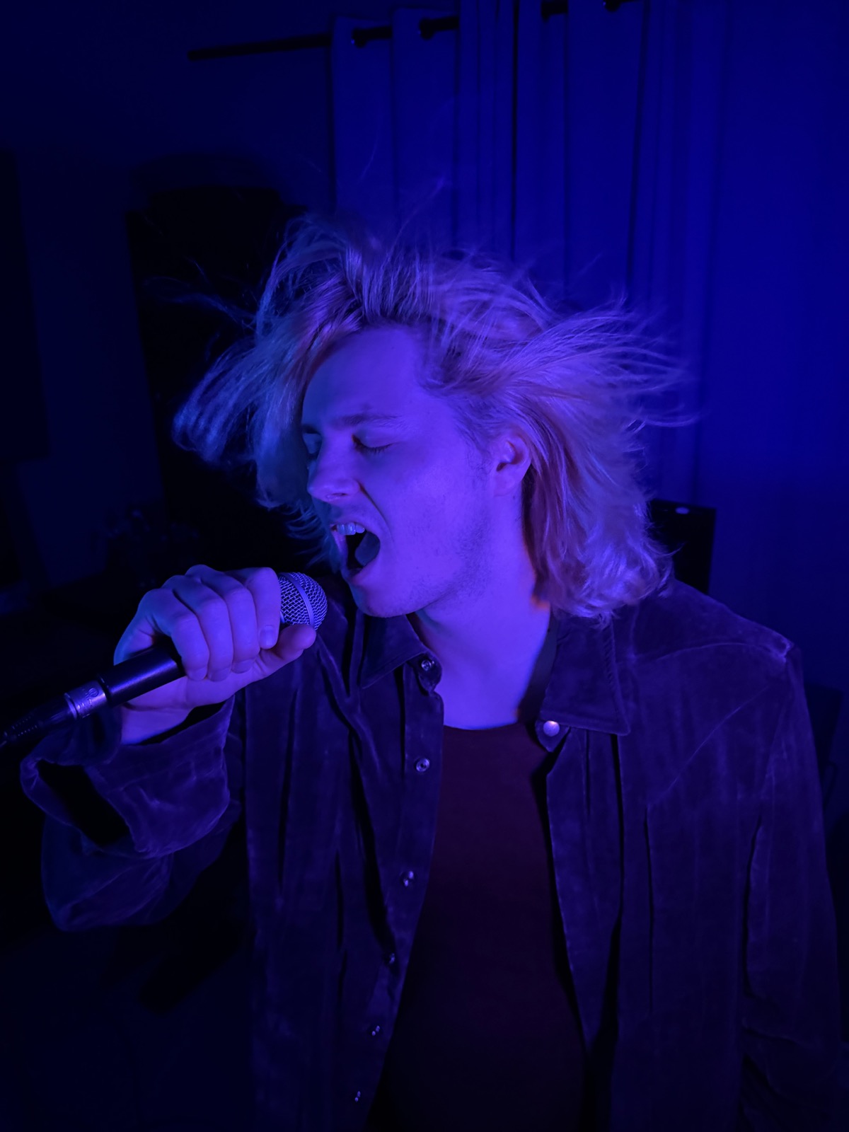 Ryan demonstrating screaming with a handheld microphone under blue light